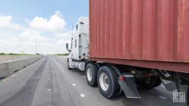 A white tractor pulling an ocean container