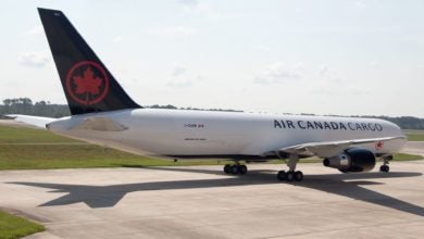 A white jet labeled Air Canada Cargo with black tail on the tarmac, viewed from the side rear.