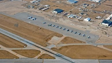 Aerial view of a large runway and partially developed area next to aircraft apron.