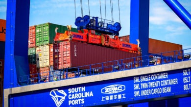 A large crane hoists an intermodal container into the air.