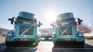 Volvo VNR Electric trucks in foreground with Ryder System badged truck in background