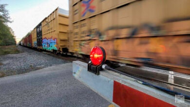 A train hauling rail cars whizzes past a railroad crossing.