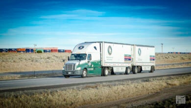 An Old Dominion less-than-truckload rig on the highway with a double-stacked intermodal train in the background