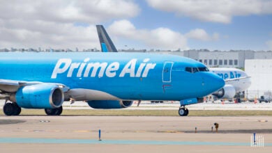 A light blue jet with Prime Air in while lettering rolls on runway on a sunny day.