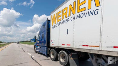 A blue Werner tractor pulling a white Werner trailer on the highway