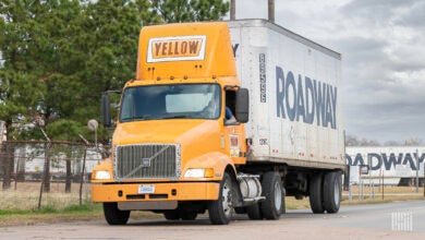 A Yellow tractor pulling a Roadway trailer