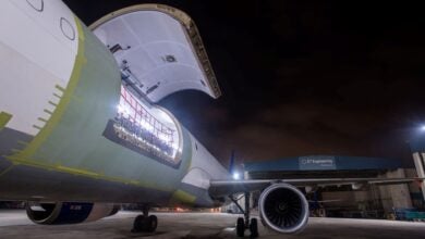 View of an open cargo door from the side of the aircraft facing to the back, at night.