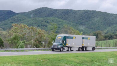 A green ABF tractor pulling two LTL trailers on a highway