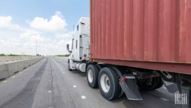 A tractor pulling an ocean container on a highway.