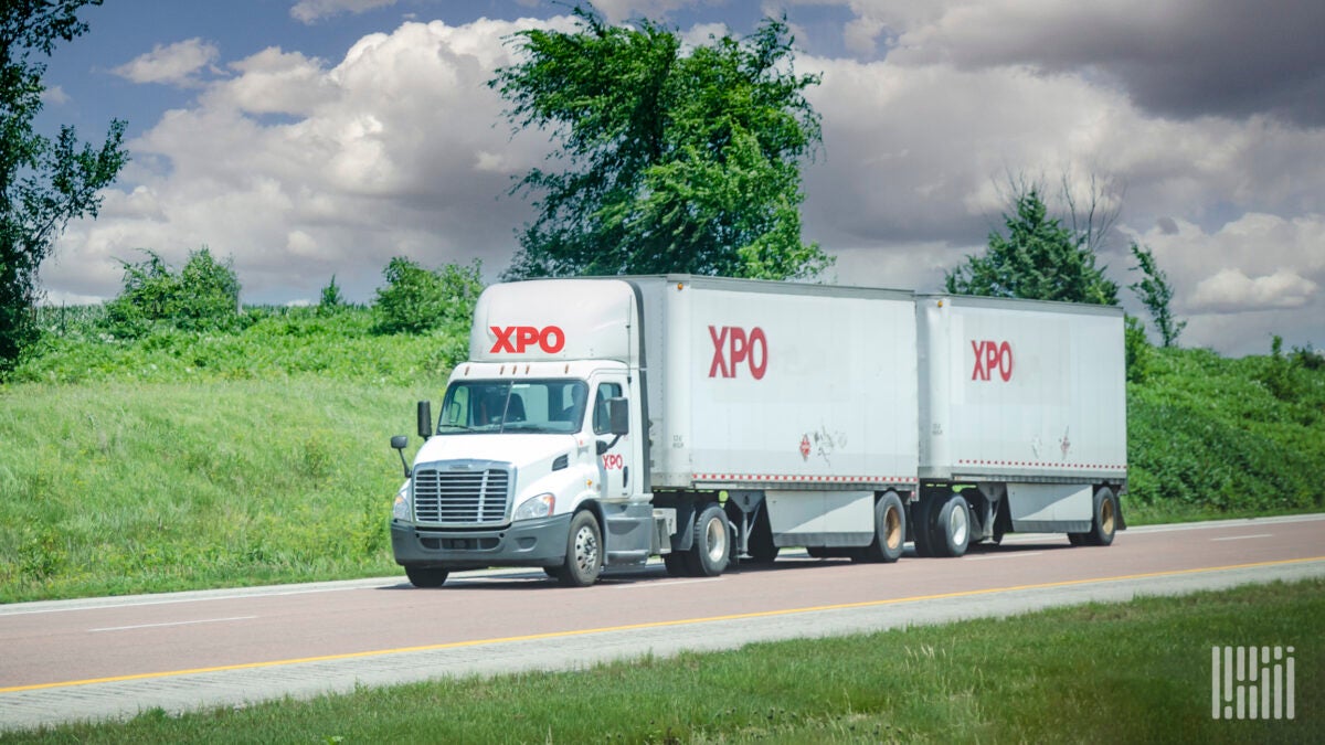 A white XPO tractor pulling two XPO LTL trailers