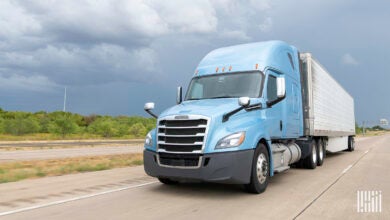 A blue tractor and a silver trailer on a highway