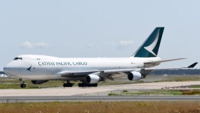 A white jumbo jet with green accents and Cathay Pacific Cargo lettering on the ground at an airport.