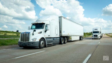 Two white tractor-trailers on highway