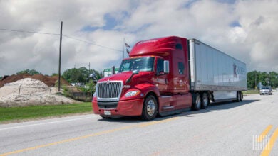 A red Knight Transportation tractor with a white trailer on the highway