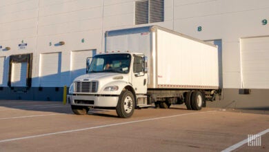 A white last-mile truck backed up to a warehouse