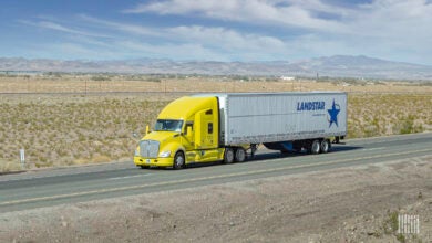 A yellow tractor pulling a white Landstar trailer