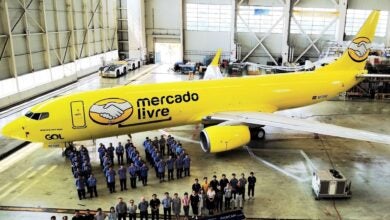 A bright yellow jet with Mercado Livre logo in a hanger with people standing in front for a picture to celebrate completed remodeling job.