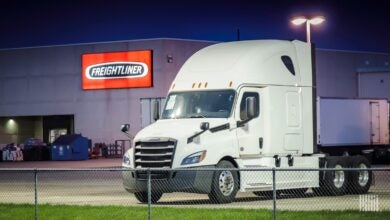 White Freightliner Cascadia and Freightliner sign in background