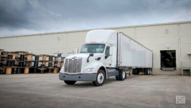 A white tractor-trailer backed into a warehouse door