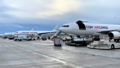 Several white CMA CGM Air Cargo aircraft with tinted windshields lined up side by side on the tarmac.