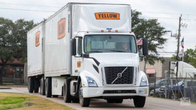 A Yellow tractor pulling two Yellow LTL trailers