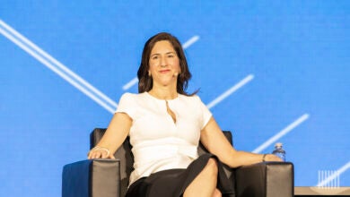 Rana Foroohar sitting in a lounge chair on stage discussing global economics.