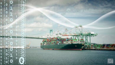 A large container shipped docked in a large bay with a bridge in the background.