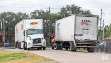 A Yellow truck and a YRC trucking passing each other at a terminal in Houston