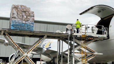 A platform lift is used to unload a pallet of cargo from a large jet.