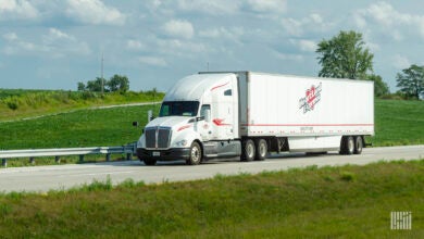 A white Heartland tractor pulling a white Heartland dry van trailer