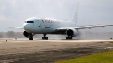 An Air Canada Cargo jet gets sprayed by water cannons to celebrate an inaugural flight at an airport.