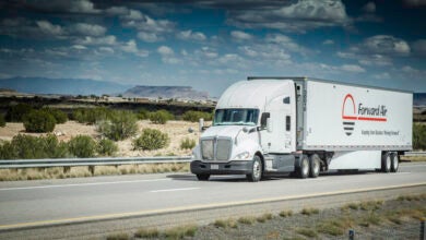 A white tractor pulling a Forward Air trailer on the highway