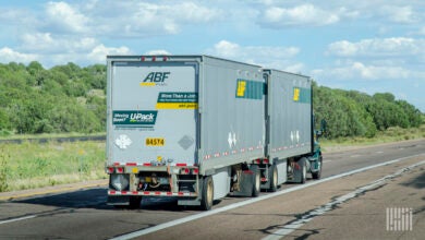 A rear view of an ABF tractor pulling two LTL trailers on a highway