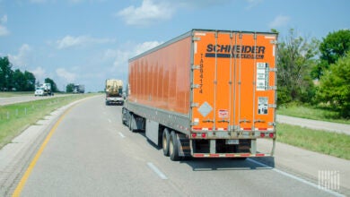 An orange Schneider trailer being pulled on a highway