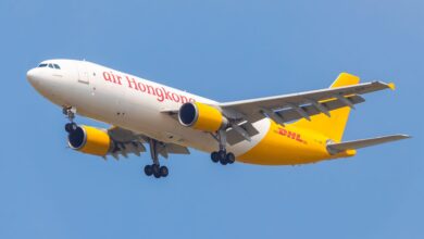 An Air Hong Kong/DHL cargo jet with a mustard-colored rear on approach with wheels down.