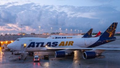 Two blue-tailed Atlas Air jumbo jets on the tarmac at dawn.