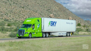 A light green Sky tractor pulling a white Sky trailer