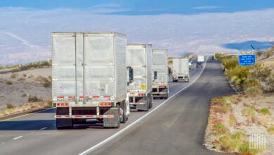 A rearview of multiple dry van trailers being pulled on a highway