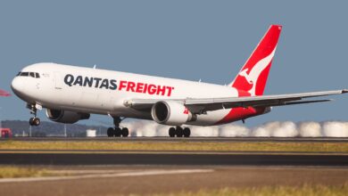 A red-tailed Qantas Freight jet touches down on a runway.