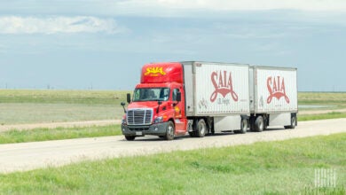 A red Saia tractor pulling two white Saia pup trailers