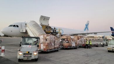 A Global X standard freighter unloads pallets of cargo at an airport.