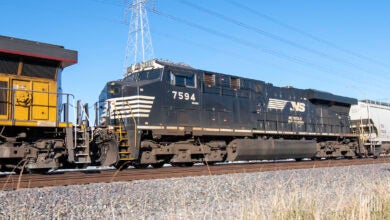 A train with the letters N S written on its side sits in a rail yard.