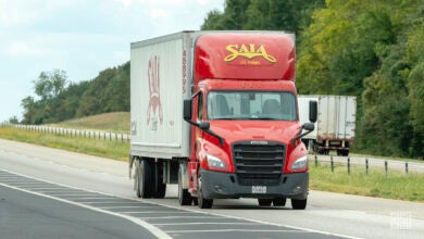 A red Saia tractor pulling a white Saia trailer on a highway