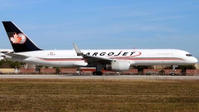 A blue-tailed Cargojet plane on an airport runway on a clear day.