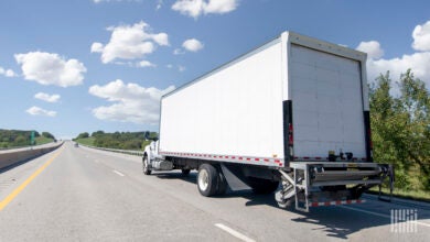 A white delivery truck with liftgate on a highway