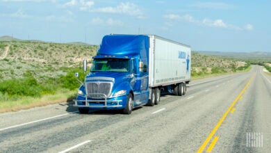 A blue tractor pulling a Landstar trailer