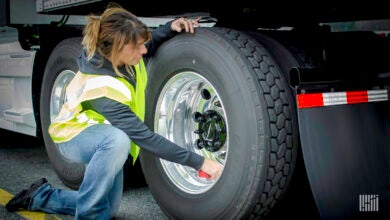 Truck driver inspecting tires.