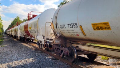 A train of tank cars passes by a railroad crossing.