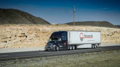 A black tractor pulling a Forward Air trailer on a highway