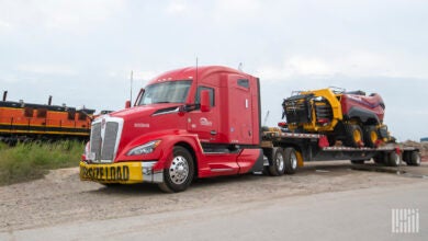 A red Lone Star tractor (Daseke company) pulling a loaded flatbed trailer